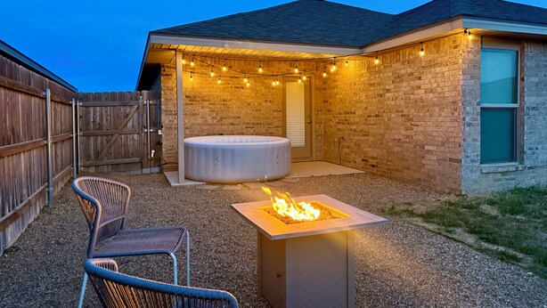 Ein Garten mit Whirlpool, Feuerstelle und Gartenmöbeln.