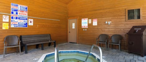 A wooden cabin with a hot tub, benches, and various posted signs.