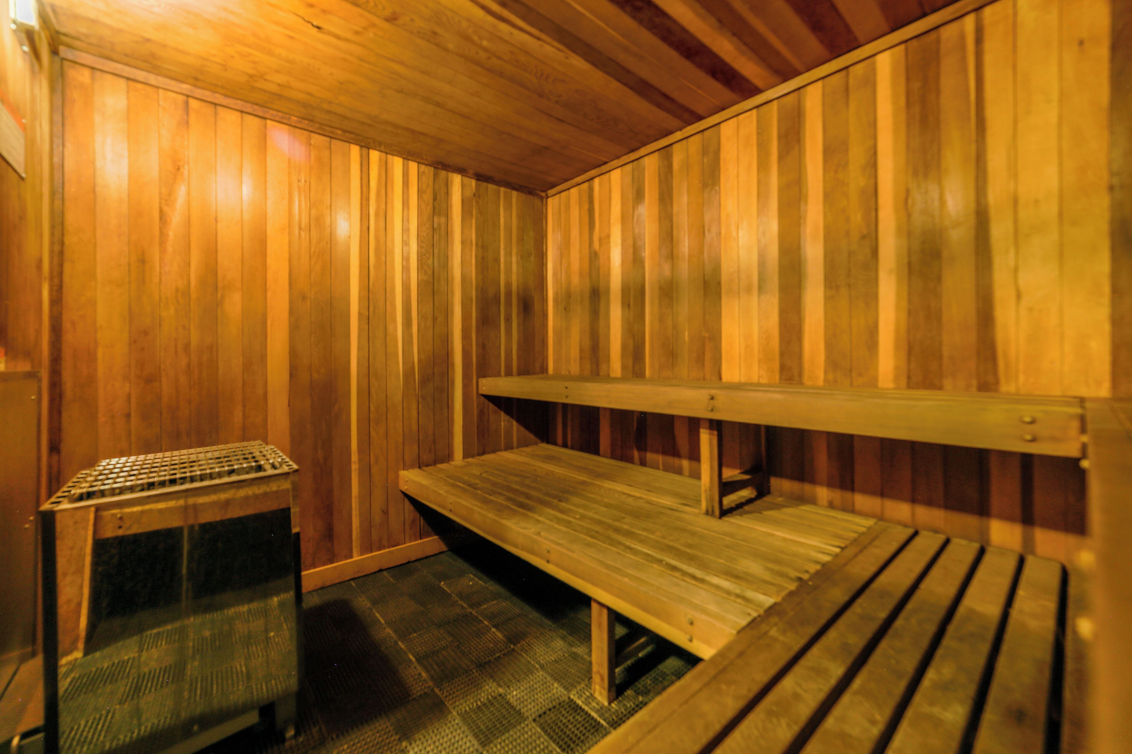 Un sauna avec des bancs en bois et une petite table, probablement destinée à accueillir des serviettes ou des effets personnels.