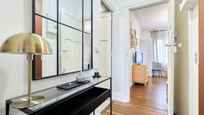 Ein stilvolles Wohnzimmer mit einem Glastischchen, einer Messinglampe und einem großen Spiegel.