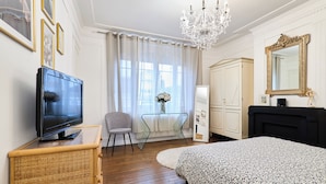 Ein Hotelzimmer mit Fernseher, Schreibtisch, Stuhl, Bett und Kleiderschrank.