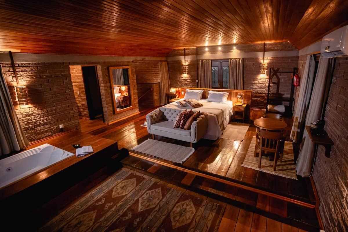 Ein geräumiges Schlafzimmer mit einem großen Bett, einer Sitzecke mit einer Couch, einem kleinen Tisch und einer Badewanne.