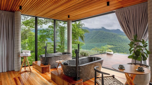 A modern spa room with wooden flooring, large windows, and a view of lush mountains. - Morada dos Canyons (Praia Grande)