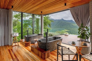 A modern spa room with wooden flooring, large windows, and a view of lush mountains. - Morada dos Canyons (Praia Grande)