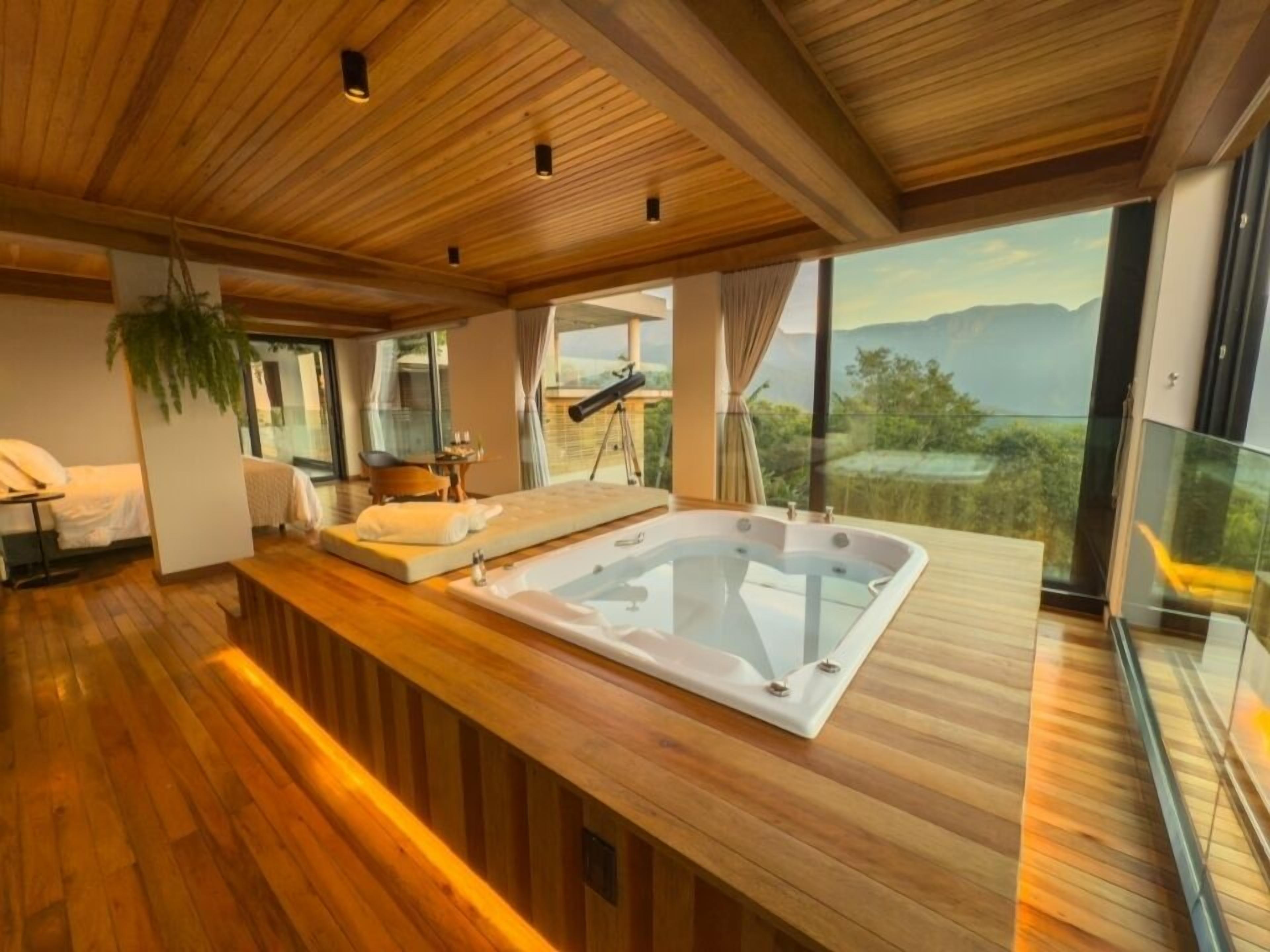 Una habitación moderna con suelo de madera, una bañera grande, un sofá y una mesa de comedor.