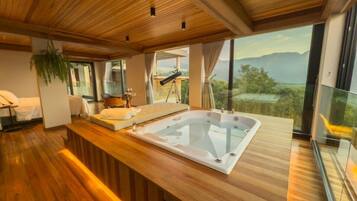 Una habitación moderna con suelo de madera, una bañera grande, un sofá y una mesa de comedor.