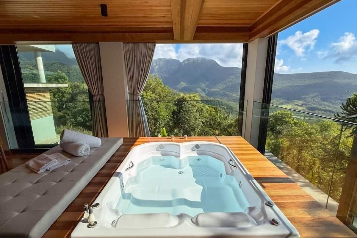 Ein modernes Schlafzimmer mit großem Fenster, Holzboden, Whirlpool und einer Couch mit Handtüchern.