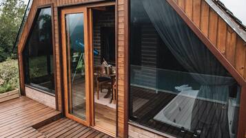 A modern wooden cabin with large glass windows and a deck.