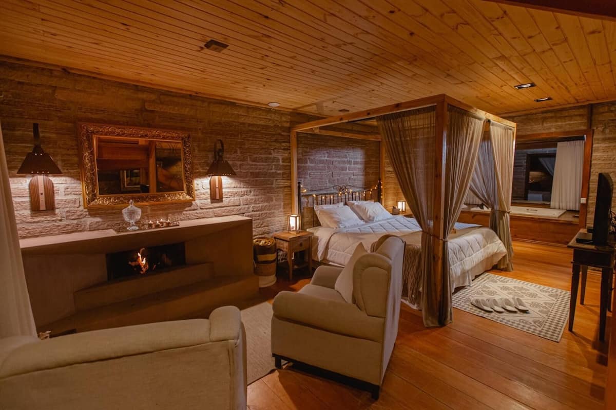 Ein gemütliches Schlafzimmer mit Himmelbett, Kamin und Steinwand.