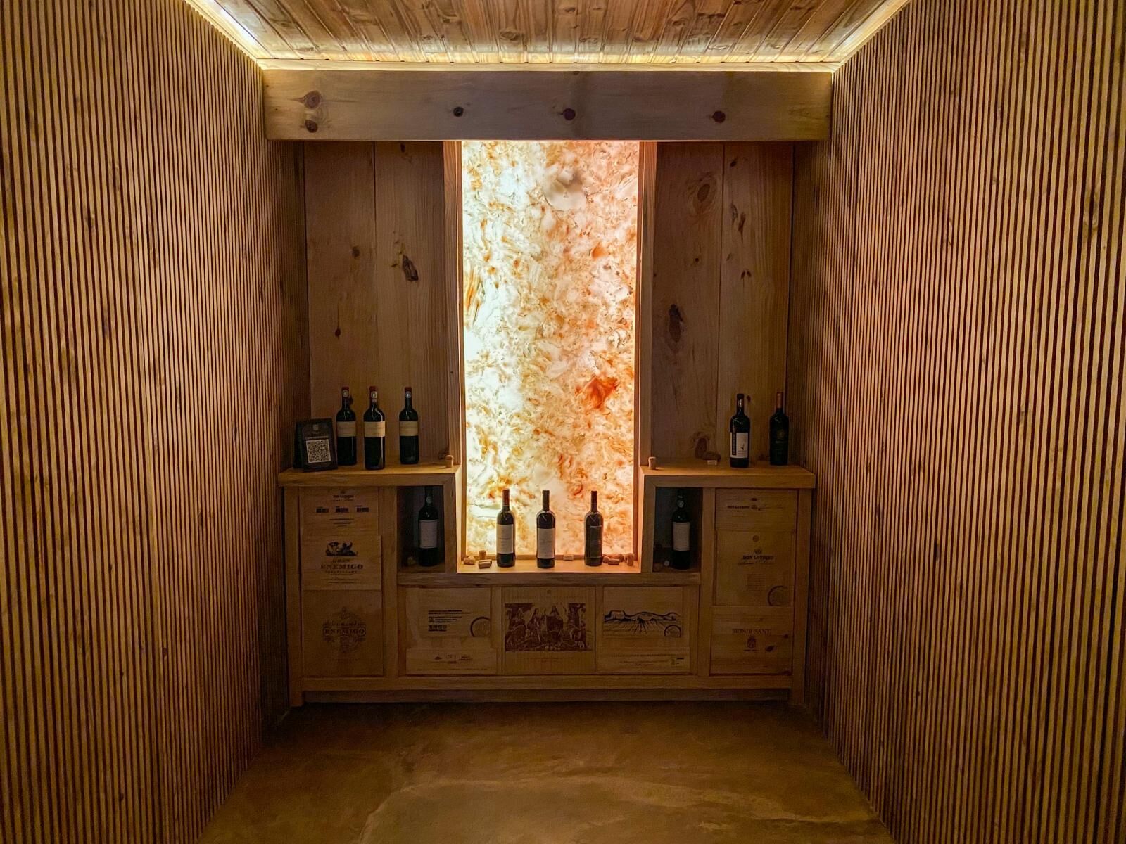 A wine cellar with wooden walls and shelves holding wine bottles.