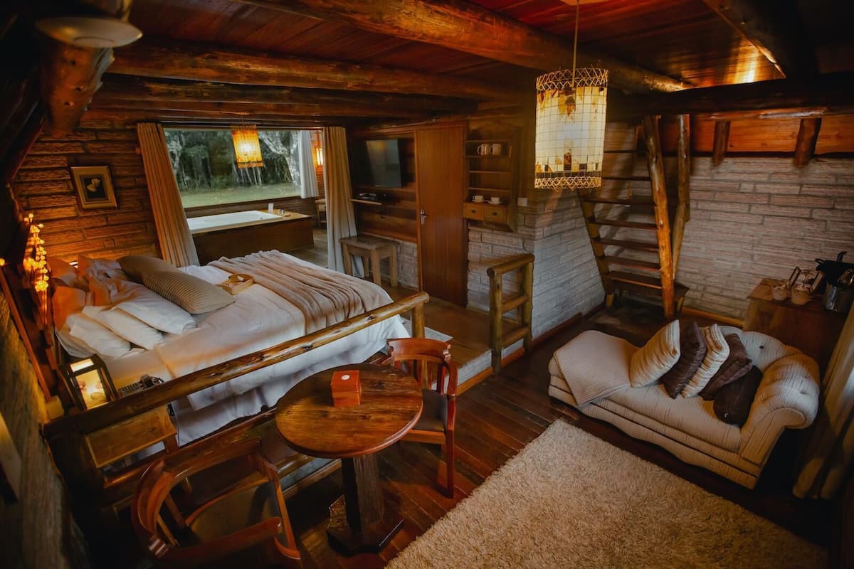 Ein gemütliches Blockhaus-Interieur mit Bett, Sofa, Esstisch und Kamin.