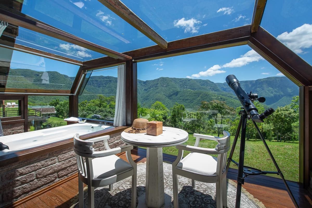 Ein Zimmer mit Glasdecke, einem Teleskop, einem Tisch und Stühlen.