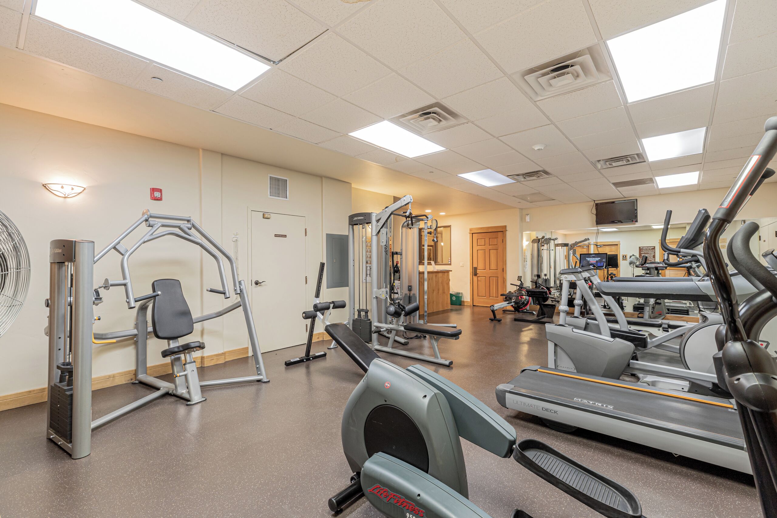 Een sportschool met diverse fitnessapparaten, waaronder loopbanden en krachttrainingsmachines.