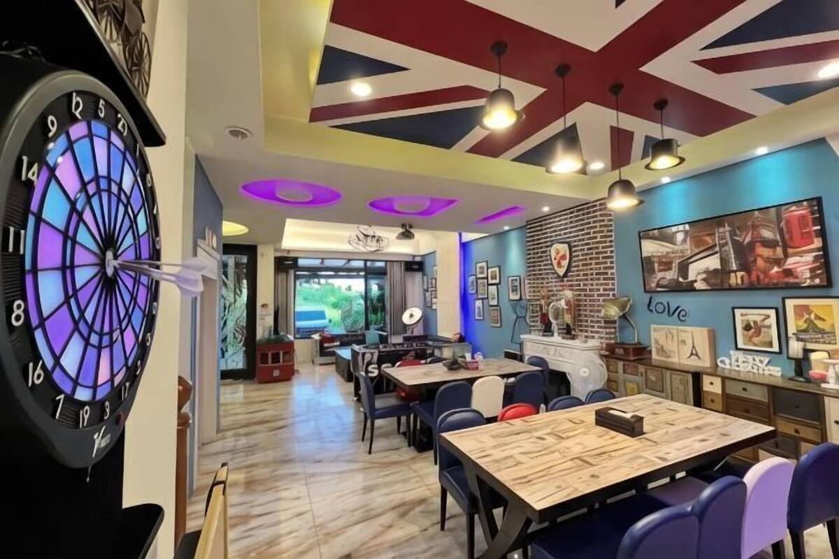 A restaurant with a dartboard, tables, chairs, and a view of the outdoors.