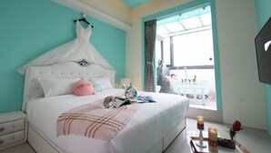 Una camera da letto con un letto bianco, un baldacchino bianco, un cuscino rosa, un comodino con un libro, una candela e un vaso con una rosa.