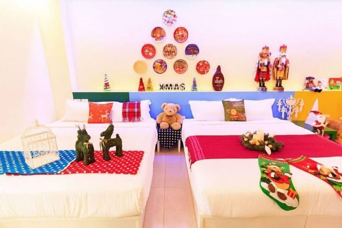 A hotel room with two beds, a teddy bear, Christmas decorations, and a wall display.