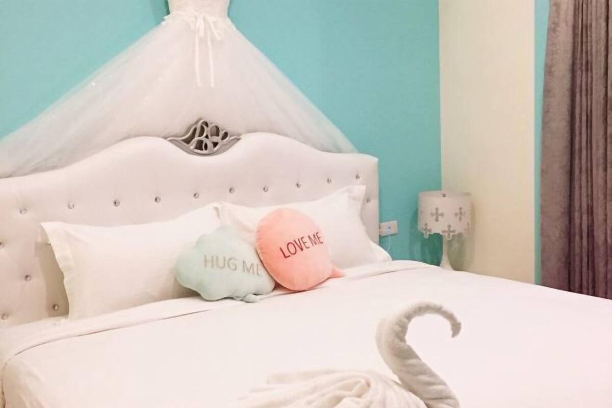 A bed with a canopy, two pillows with text, and a decorative item resembling a swan.