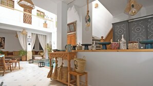 A spacious living area with a pool, wooden furniture, and decorative items on shelves. - Riad Larbi Khalis (Marrakech)
