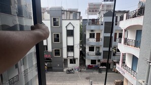 A residential area with multi-story buildings, a visible balcony, and a parked motorcycle. - HOTEL RUDRAKSH (Rahata)