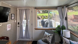 A cozy room with a TV, a couch, a small table, and a window with curtains.