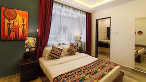 A modern hotel room with a large bed, a bedside table with a lamp, a mirror, and a painting on the wall. - Trisan Resident Hotel (Nairobi)