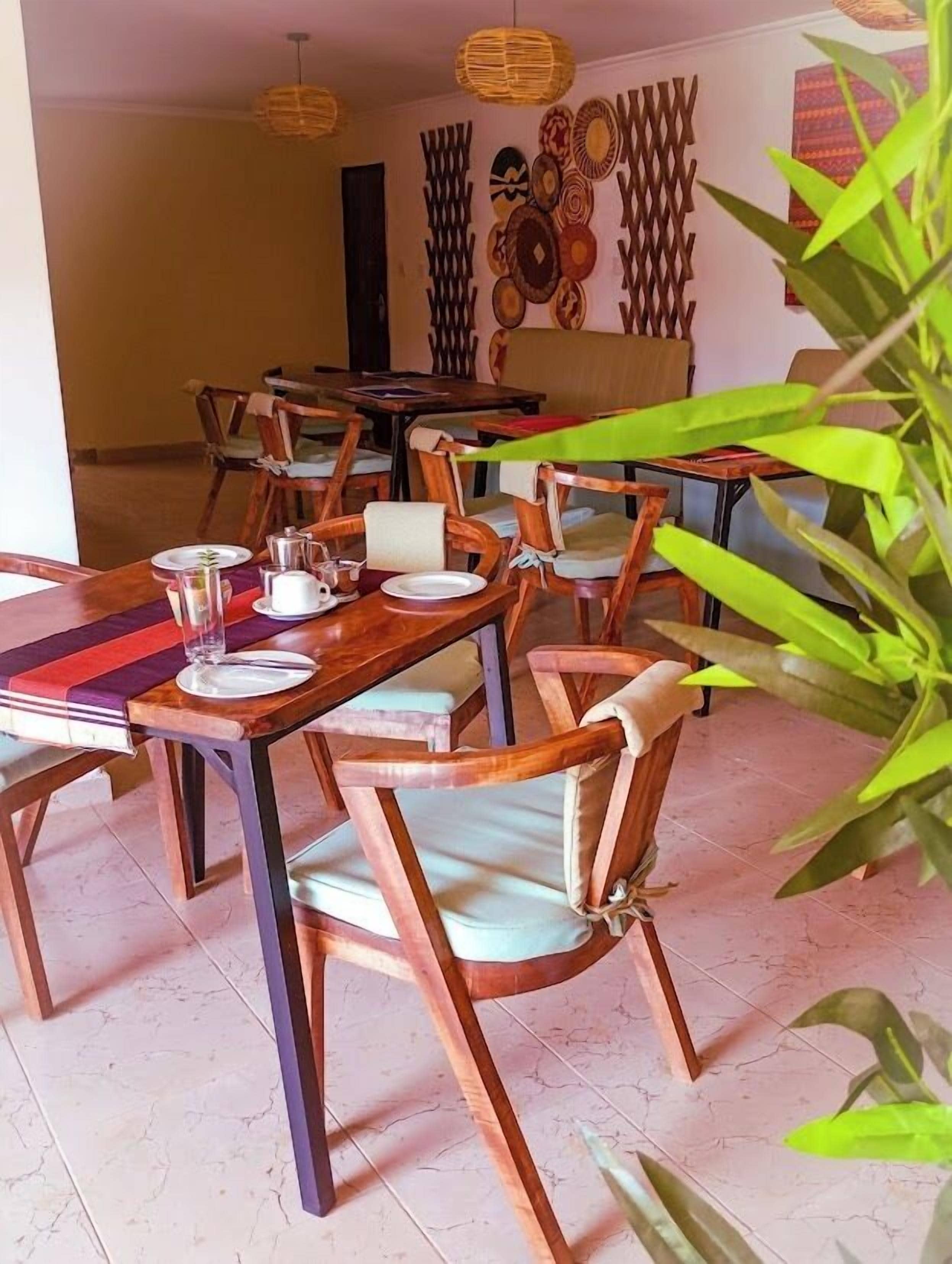 Un comedor con mesas y sillas de madera, suelo de baldosas y decoración mural.