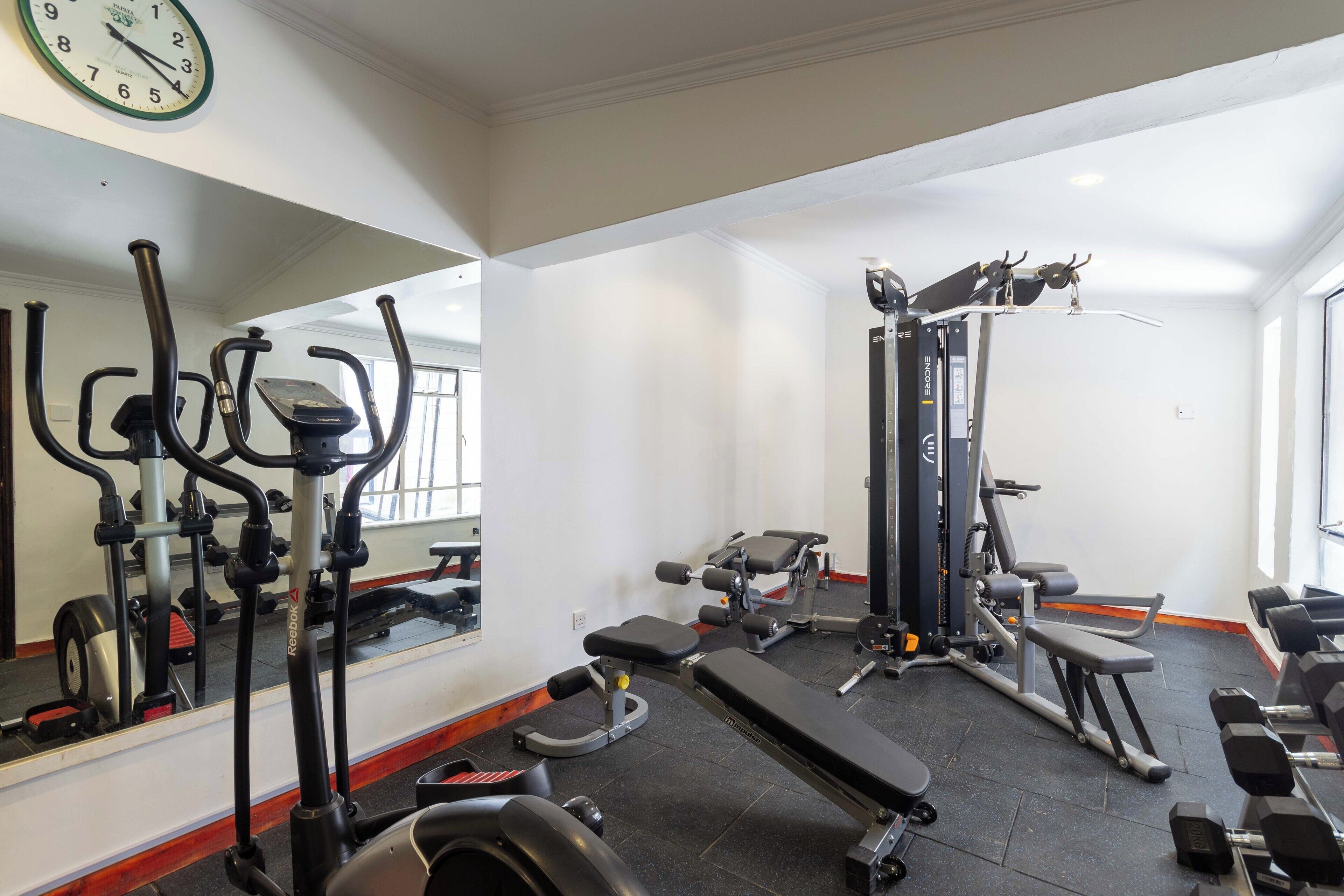 A gym with exercise equipment, a bench, and a mirror.