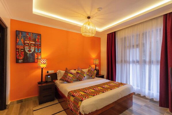 A modern hotel room with a large bed, a nightstand, a lamp, and a painting on the wall.