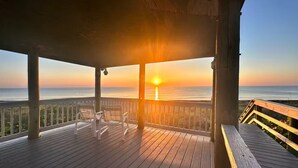 A wooden deck with chairs facing the ocean at sunset. - 2 bedroom 2 Bath Home w/Pool and beach access! (Jensen Beach)