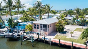 A coastal property with a dock, boats, and a small building with a balcony. - 2 bedroom 2 Bath Home w/Pool and beach access! (Jensen Beach)