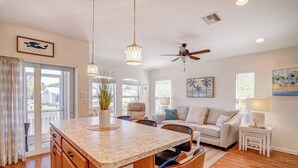 A spacious living area with a large island, a ceiling fan, and a view through the glass doors. - 2 bedroom 2 Bath Home w/Pool and beach access! (Jensen Beach)