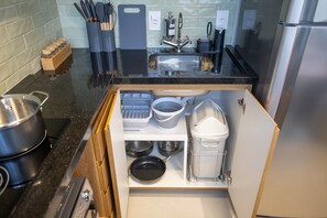 A kitchen with a built-in sink, a stove, and a storage cabinet with pots and pans. - Vida Madalena (Sao Paulo)
