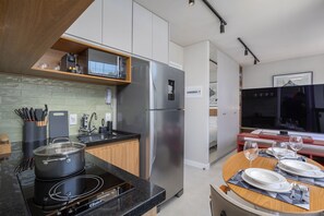 A modern kitchen with a built-in stove, stainless steel refrigerator, and a microwave on a wooden shelf. - Vida Madalena (Sao Paulo)