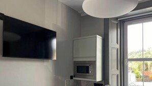 Une cuisine équipée d’un four à micro-ondes et d’un téléviseur à écran plat fixé au mur.