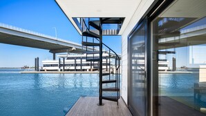 Un edificio moderno con fachada de vidrio que da a una gran piscina y un puente.
