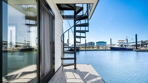 Un edificio moderno con fachada de vidrio, una escalera metálica y vistas a un puerto deportivo con barcos.