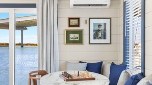 Una habitación acogedora con una mesa redonda de mármol, sillas de madera, un sofá con cojines azules y cuadros enmarcados en la pared.