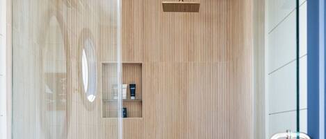 A modern bathroom with a shower, a vanity with a marble countertop, and a glass shower enclosure.