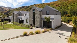 A modern two-story house with a stone facade, a garage, and a well-maintained front yard with a pathway.