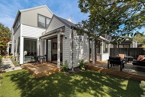 Una casa moderna con un porche cubierto, césped y mobiliario de exterior.