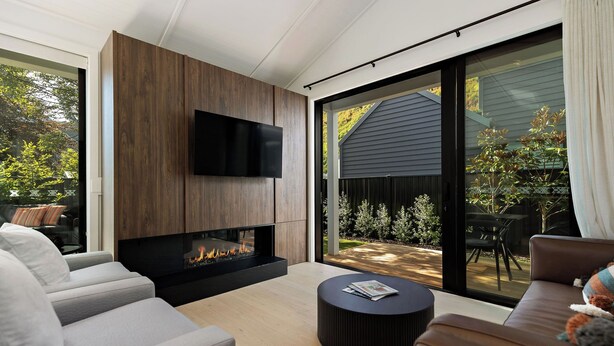 A modern living room with a fireplace, a flat-screen TV, and a comfortable seating area.