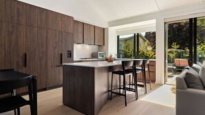 A modern kitchen with a central island, dark wooden cabinets, and a large window providing a view of the outdoors.