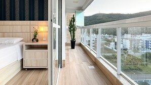 A modern bedroom with a bed, bedside table, lamp, and a potted plant. - Amplo apartamento em Palmas (Governador Celso Ramos)