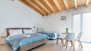 A bedroom with two beds, a dining area with a table and chairs, and a large window. - NICA&DAMA fully equipped apartment with 5 beds (Palermo)