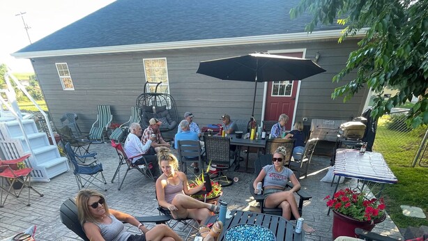 Een terras buiten met zitplaatsen, een barbecue en potplanten.