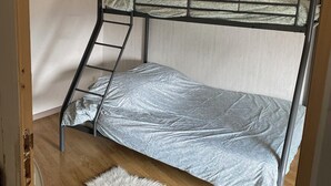 Een stapelbed met een ladder, een zachte witte vloerkleden en een hanglamp.