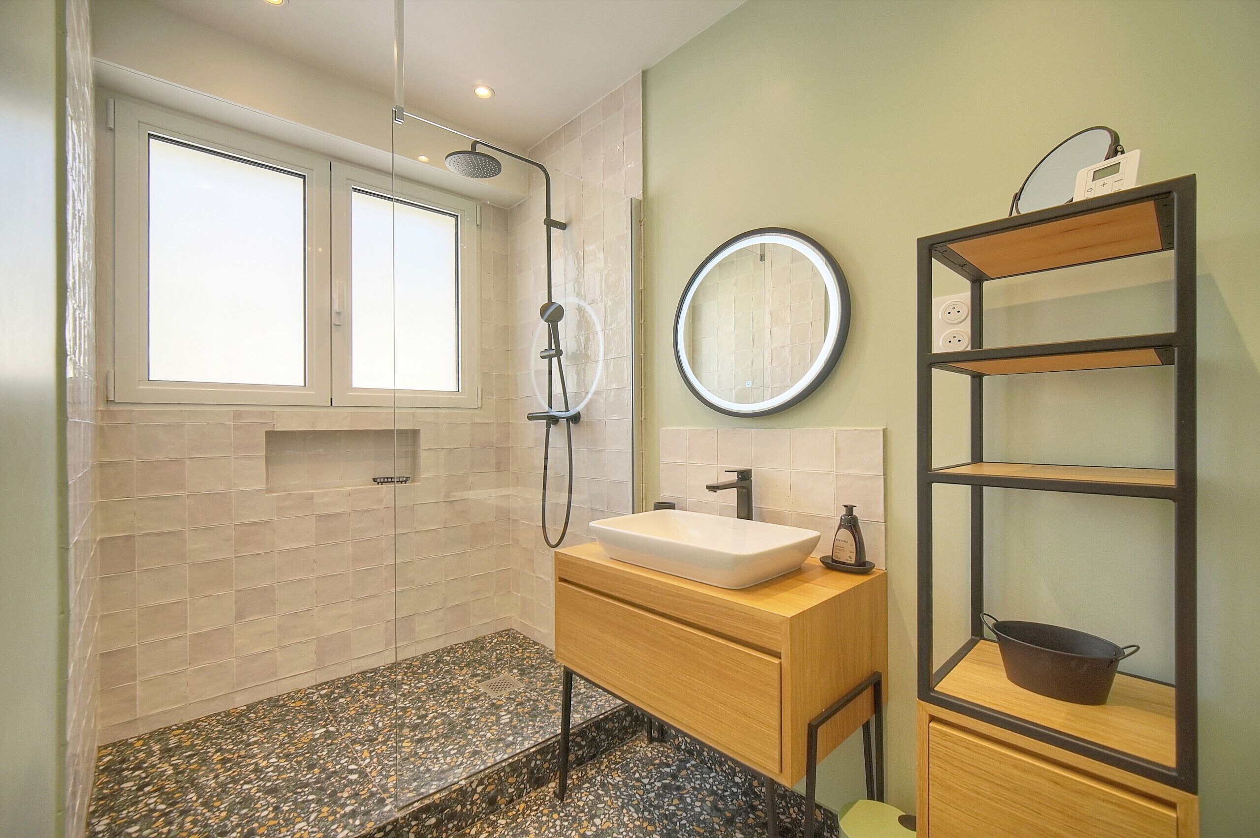 Une salle de bain moderne avec une douche, un lavabo et un miroir.