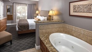 Ett hotellrum med en stor säng, en sittgrupp med en bänk, ett badkar och ett skrivbord med en stol.