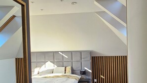 A modern bedroom with a wooden floor, a bed with a headboard, a bedside table, and a nightstand.