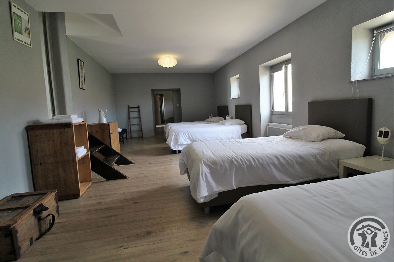 A hotel room with two beds, a wooden dresser, a ladder, and a small table.